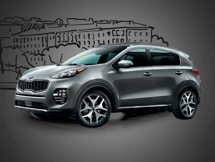 Серый автомобиль Kia Sportage на фоне города.